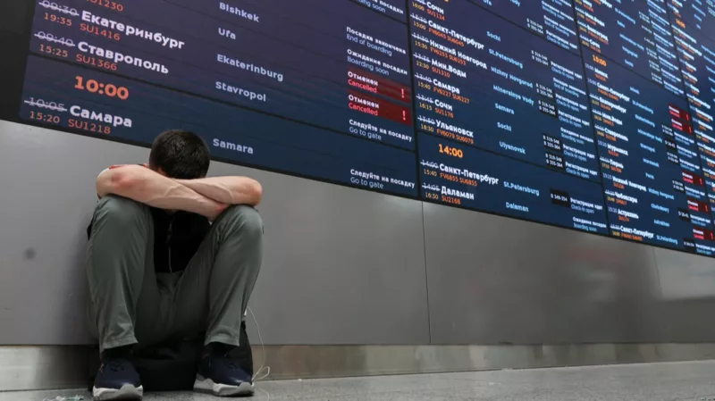 Цены на авиабилеты начинают стремительно расти по всему миру! 2 Человек сидит у табло аэропорта.